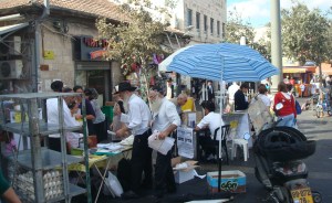 Jews selling lots of jewish  texts, praying-strops and ropes and hats